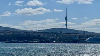 Çamlıca Tower rises above Istanbul’s hillside skyline beyond the sparkling Bosphorus, with a cruise ship at the right.