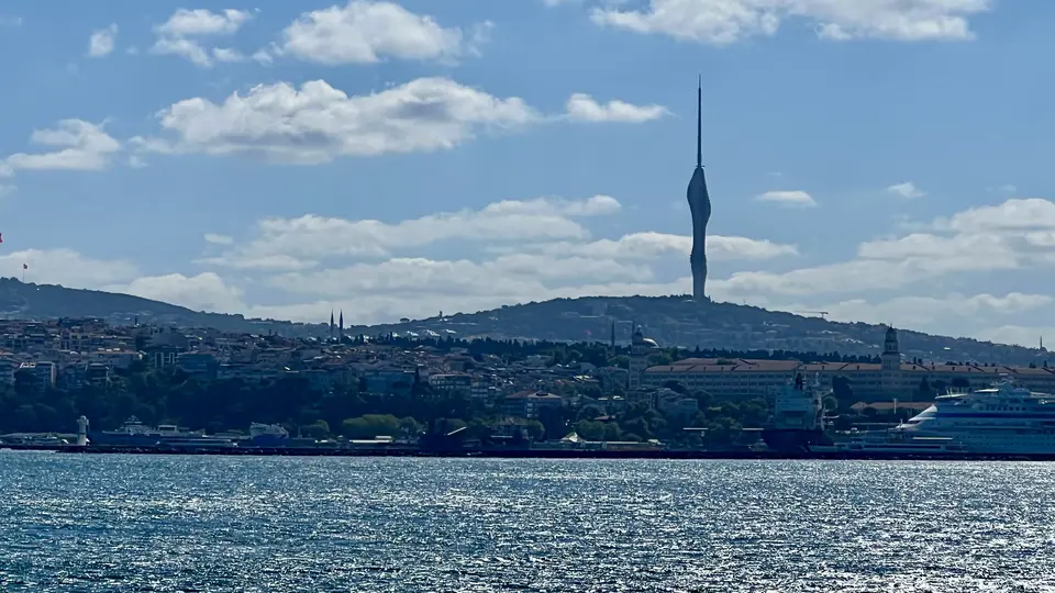 Çamlıca Tower rises above Istanbul’s hillside skyline beyond the sparkling Bosphorus, with a cruise ship at the right.