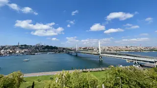 The Haliç Metro Bridge spans the Golden Horn beneath a bright blue sky, with Istanbul’s hillside skyline in the distance.