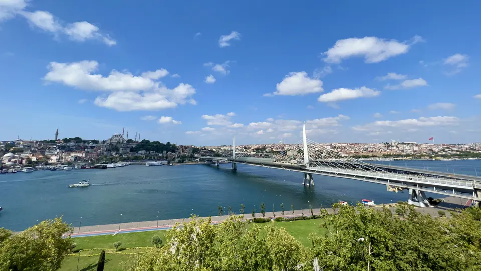 The Haliç Metro Bridge spans the Golden Horn beneath a bright blue sky, with Istanbul’s hillside skyline in the distance.