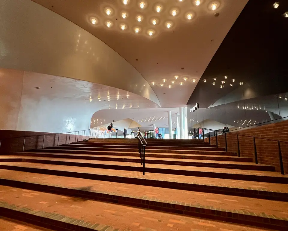 Broad brick steps rise beneath a sweeping curved ceiling lined with warm lights in a modern interior.