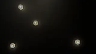 Four recessed ceiling lights glow against a dark ceiling.