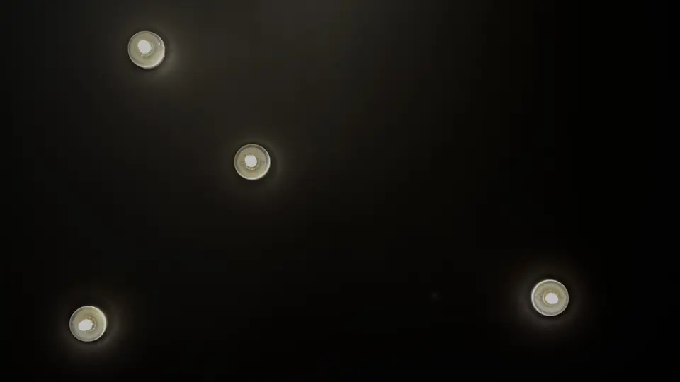 Four recessed ceiling lights glow against a dark ceiling.